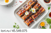Вкусные рулетики из угря на гриле с цветочным декором на чистом белом фоне для кулинарного дизайна. Стоковое AI-изображение, AI-художник ФотоИнтеллект / Фотобанк Лори