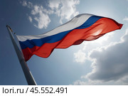The flag of the Russian Federation on the flagpole proudly flutters in the wind against the backdrop of the blue sky. Стоковое AI-изображение, AI-художник Сергей Елизарьев / Фотобанк Лори