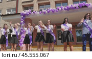 Female graduates saying farewell on their final school day, adorned with purple ribbons and surrounded by festive balloons. Стоковое видео, видеограф Mikhail Davidovich / Фотобанк Лори