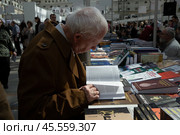 06.04.2023, Москва. Международная ярмарка интеллектуальной литературы «non/fictioNвесна» в Гостином дворе. Пожилой мужчина читает книгу. Редакционное фото, фотограф Дмитрий Киселёв / Фотобанк Лори