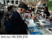06.04.2023, Москва. Международная ярмарка интеллектуальной литературы «non/fictioNвесна» в Гостином дворе. Мужчина рассматривает книгу на прилавке. Редакционное фото, фотограф Дмитрий Киселёв / Фотобанк Лори
