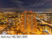 City skyline illuminated at night with residential buildings and vibrant lights in a bustling urban landscape. Tall residential building surrounded by twinkling lights from various structures (2017 год). Стоковое фото, фотограф Алексей Климкин / Фотобанк Лори
