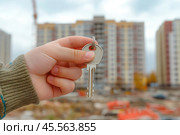 Мужская рука держит ключ от квартиры на фоне строящегося дома. Стоковое AI-изображение, AI-художник Ярославский Максим / Фотобанк Лори
