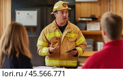 Firefighter leading briefing with digital tablet in fire station meeting room. Стоковое AI-изображение, AI-художник Юрий Поздников / Фотобанк Лори
