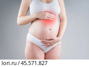 Pregnant woman with abdominal pain, risk of premature birth, gray background. Стоковое фото, фотограф Станислав Тарко / Фотобанк Лори
