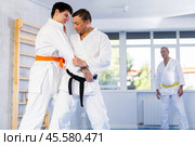 Jiu-jitsu master demonstrating basic grabs and throws in sparring with young fighter. Стоковое фото, фотограф Яков Филимонов / Фотобанк Лори