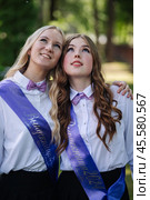 Two ecstatic graduates in sashes gaze at the sky, rejoicing in the completion of their studies and their final day of school. Стоковое фото, фотограф Mikhail Davidovich / Фотобанк Лори
