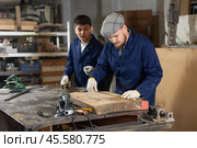 Carpenter measures the length of board with tape measure. Foreman prompts him. Стоковое фото, фотограф Яков Филимонов / Фотобанк Лори