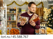 Young man picking out traditional Spanish sweets for Christmas celebration. Стоковое фото, фотограф Яков Филимонов / Фотобанк Лори