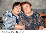 Two cheerful women, aged 70 and 60, share a warm moment together. Capturing friendship, happiness and beauty of aging gracefully. Perfect for themes of senior companionship and life celebrations. Стоковое фото, фотограф Татьяна Терехина / Фотобанк Лори