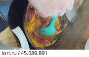 A woman adds tomato paste to the carrots in the pan. Vertical video. Стоковое видео, видеограф Vadzim Yakubovich / Фотобанк Лори