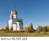 Владимирская церковь возвышается в селе Стуковолово, олицетворяя красоту православной архитектуры на фоне осеннего пейзажа с яркими деревьями. Каменный крест около захоронения. Стоковое фото, фотограф Сергей Никифоров-Гордеев / Фотобанк Лори