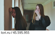 Supportive student comforting her crying friend leaning against a wall in a school hallway. Стоковое видео, видеограф Mikhail Davidovich / Фотобанк Лори