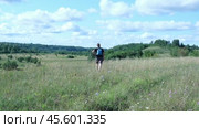 Exploring Nature a Hiker with backpack Strolling Through a Beautiful Field Beneath Vast Blue Sky. Tourist man traverses a scenic field, clear blue sky. Adventure and exploration concept. One person. Стоковое видео, видеограф Марина Демидюк / Фотобанк Лори