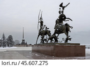 Скульптурная композиция «Царская охота» и обелиск «Центр Азии», город Кызыл, Республика Тыва (Тува), Сибирь, Россия. Скульптурное изображение двух всадников — мужчины и женщины, на соколиной охоте. Рядом с ними бегут две охотничьи собаки. На дальнем плане обелиск в виде шара со шпилем. Зимний пейзаж с памятниками. Сквер Центр Азии на набережной имени К.С. Шойгу. Туристические достопримечательности Кызыла. Редакционное фото, фотограф Андрей Степанов / Фотобанк Лори