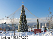 Красивая рождественская ёлка в заснеженном городском парке. Парк Ходынское поле, город Москва, Россия. Высокая новогодняя ель, украшенная шарами, снежинками и гирляндами. Искусственная ёлка, установленная на улице под открытым небом. На тумбах текст «С Новым годом, Москва!». Праздничное новогоднее и рождественское настроение. (2024 год). Редакционное фото, фотограф Андрей Степанов / Фотобанк Лори
