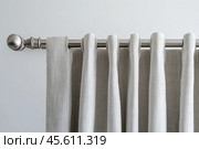 Curtain rod. Curtain on a metal rod with grommets close up. Bracket for curtain rod eaves and pole against white backdrop. Soft flowing fabric. Simple elegant design. Metal clip guide for window tulle. Стоковое AI-изображение, AI-художник Марина Демидюк / Фотобанк Лори
