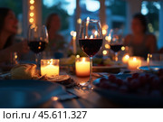 Christmas Holiday Dining. Festive table setting with exquisite wine and romantic candlelight at holiday gatherings. Cutlery set with intricate designs. Seasonal holiday dining background. Family Meal. Стоковое AI-изображение, AI-художник Марина Демидюк / Фотобанк Лори