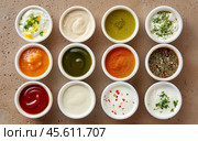 Large collection of sauces and spiced spreads in small jars. Big Set of colored dipping sauces in Crockery. Different types of dressing, mayonnaise, mustard, soy sauce, oil and ketchup on a black. Стоковое AI-изображение, AI-художник Марина Демидюк / Фотобанк Лори