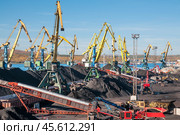 Горы угля в морском порту, грузовые вагоны из под угля, телескопические ленточные транспортеры, которые перераспределяют уголь по участку. Стоковое фото, фотограф Павел Просянов / Фотобанк Лори