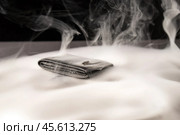 Black leather wallet resting on a dark backdrop, surrounded by swirling smoke. Money appears to be burning, symbolizing fleeting wealth and the transient nature of material possessions. Стоковое фото, фотограф Татьяна Степанищева / Фотобанк Лори