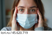 Девушка в маске держится за голову. Концепция болезни. Стоковое AI-изображение, AI-художник Илья Старков / Фотобанк Лори
