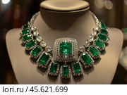 Emerald and diamond necklace sparkling on display mannequin. Стоковое AI-изображение, AI-художник Иван Рябоконь / Фотобанк Лори