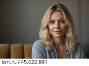 Head shot portrait pretty blonde woman looking at camera, sits alone on sofa photoshooting, enjoy pleasant pastime weekend at home at own or rented apartment. Beautiful mature female profile picture. Стоковое AI-изображение, AI-художник Александр Поташев / Фотобанк Лори
