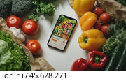 Fresh vegetables surround smartphone displaying grocery app interface for healthy shopping. Стоковое AI-видео, аниматор Sabyna75 / Фотобанк Лори