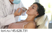 Middle-aged female patient lying on clinical chair undergoing face care procedure by injection method. Стоковое видео, видеограф Яков Филимонов / Фотобанк Лори