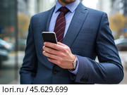 Man in business suit holds smartphone in his hands. Стоковое AI-изображение, AI-художник Klimiankova Tatsiana / Фотобанк Лори