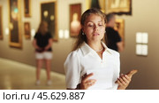 Woman with sheet piece of paper in hands view pictures and icons in museum hall. Стоковое видео, видеограф Яков Филимонов / Фотобанк Лори