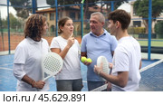 Group of cheerful paddle tennis players on different ages standing on open court after match on summer day and friendly talking. Стоковое видео, видеограф Яков Филимонов / Фотобанк Лори