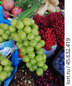 Разнообразие свежих продуктов на рынке. Крупный план на рынке с крупным зелёным виноградом, черникой, грецкими орехами, красной рябиной, гранатами и корнеплодами. На заднем плане свежая зелень и овощи. Стоковое фото, фотограф Анна Чижова / Фотобанк Лори