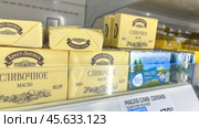 Moscow December 04, 2024, Butter in packaging on a store counter. Concept of increasing prices for butter. Refrigerator in a grocery store with briquettes of natural butter. Редакционное фото, фотограф Скрипачев Антон / Фотобанк Лори