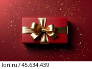 Perfect red Christmas present gift box with elegant gold bow ribbon on red background near stars. Greeting gift symbolize lovely holiday gifting. Birthday Christmas festive concept. Copy ad text space. Стоковое AI-изображение, AI-художник Aleksandr Golubev / Фотобанк Лори