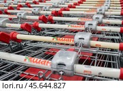 Moscow, Russia, June 2020: Close-up of a coin-operated receiver on the handles of Auchan shopping carts with locks. Редакционное фото, фотограф Юлия Ильина / Фотобанк Лори