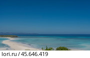 Beautiful postcard seascape. A sandbar winds through the aquamarine ocean to a small green island. Silhouettes of people on the beach. Boats on the water. Mountains on the horizon. Clear blue sky. Стоковое фото, фотограф Вера Ивановна Кубарева / Фотобанк Лори