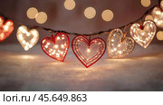 The concept of Valentine's Day, a banner with garlands in the form of hearts and magic lights for a holiday filled with love. A place for the text. Стоковое AI-изображение, AI-художник Photojuli / Фотобанк Лори