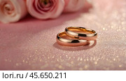 Gold wedding rings on a pink background with a side. Wedding rings. The wedding day. The newlyweds. Стоковое AI-изображение, AI-художник Photojuli / Фотобанк Лори