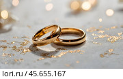 Gold wedding rings on a white background with a side. Wedding rings. The wedding day. The newlyweds. Стоковое AI-изображение, AI-художник Photojuli / Фотобанк Лори