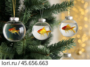 Goldfish in balls as Christmas tree decorations on a decorated New Year tree. Fulfillment of wishes. New Year's card. Стоковое AI-изображение, AI-художник Сергей Комаров / Фотобанк Лори