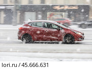 Dangerous car drive on highway at heavy snowy conditions. Red Kia Ceed  in motion on winter city street. Редакционное фото, фотограф Константин Григорьев / Фотобанк Лори