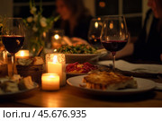 Christmas Holiday Dining. Festive table setting with exquisite wine and romantic candlelight at holiday gatherings. Cutlery set with intricate designs. Seasonal holiday dining background. Family Meal. Стоковое AI-изображение, AI-художник Марина Демидюк / Фотобанк Лори