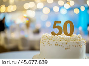 50th birthday cake adorned a gold accents. Birthday party. Blurred light festive background. Golden balloons. Fifty years, Fiftieth anniversary. Celebration cake, golden candles. Numbers 50. Стоковое AI-изображение, AI-художник Марина Демидюк / Фотобанк Лори