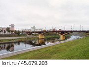 Красивый Кировский мост через реку Западная Двина в центре Витебска. Белоруссия. Склон к реке с зеленым газоном. Осенние деревья с желтой листвой. Редакционное фото, фотограф Сергей Никифоров-Гордеев / Фотобанк Лори