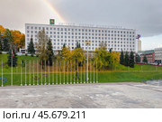 Административное здание с лозунгом на Белорусском языке на центральной улице Витебска в районе летнего амфитеатра. Осенние деревья окрашены в желтые и оранжевые цвета, создавая теплую атмосферу. Радуга над зданием - хорошая примета. Редакционное фото, фотограф Сергей Никифоров-Гордеев / Фотобанк Лори