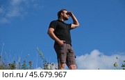 Handsome confident man standing with arms crossed among blue sky background. Male looking proud showing vision, ambition, success with arms folded. Bearded man wearing sunglasses, black polo t-shirt. Стоковое видео, видеограф Марина Демидюк / Фотобанк Лори