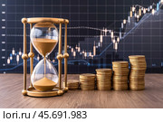 Hourglass with columns of coins on growth chart background. Стоковое AI-изображение, AI-художник Сергей Комаров / Фотобанк Лори