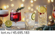 Festive Holiday Cocktails. Glasses of cocktails with Christmas decoration on bokeh lights background. Season drink set. Vibrant colorful display of various winter cocktails for New Year celebrations. Стоковое видео, видеограф Марина Демидюк / Фотобанк Лори